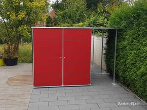 Ein roter Gartenschrank mit Flachdach steht auf einer Terrasse, umgeben von Bäumen und Hecken.