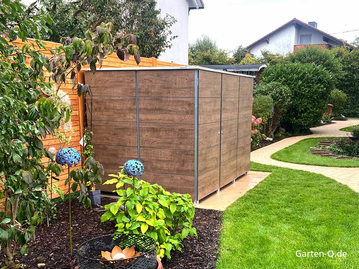 Ein Holzschuppen im Garten mit Pflanzen, bunten Glasdekorationen und einem geschwungenen Weg.